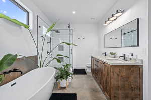 Full bathroom featuring separate shower and tub, vanity, concrete floors, and toilet