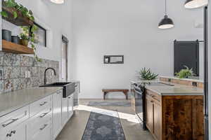 Kitchen featuring white cabinetry, sink, a barn door, black / electric stove, and pendant lighting