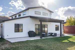 Back of house with outdoor lounge area, a patio area, and a lawn