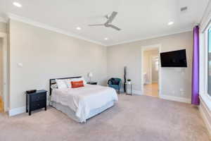 Bedroom featuring ceiling fan, light colored carpet, crown molding, and connected bathroom