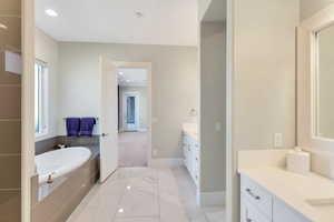 Bathroom featuring vanity, crown molding, and tiled tub