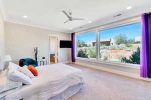 Bedroom with light colored carpet, ceiling fan, and crown molding