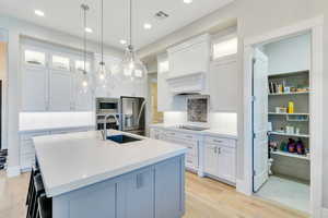 Kitchen with white cabinetry, stainless steel appliances, and a kitchen island with sink