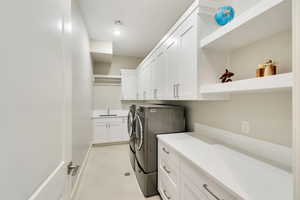 Washroom with cabinets, separate washer and dryer, and sink