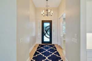 Foyer entrance with light hardwood / wood-style flooring and an inviting chandelier