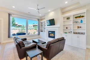 Living room with ceiling fan, a fireplace, light hardwood / wood-style floors, and built in features