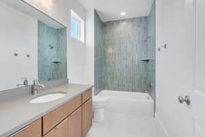 Full bathroom with vanity, tiled shower / bath combo, and toilet