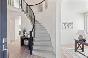 Stairs with hardwood / wood-style floors and a towering ceiling