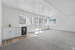 Interior space with sink, white cabinets, beverage cooler, and a textured ceiling