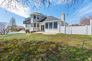 Rear view of property with a yard, a patio, and a balcony