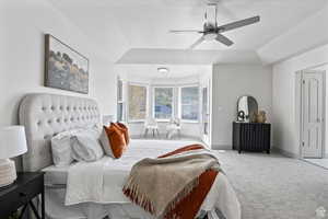 Carpeted bedroom featuring ceiling fan and vaulted ceiling