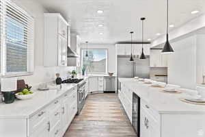 Kitchen featuring light stone countertops, decorative light fixtures, white cabinetry, and high quality appliances