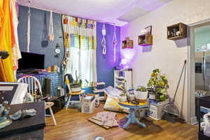 Bedroom with stainless steel refrigerator with ice dispenser and wood-type flooring