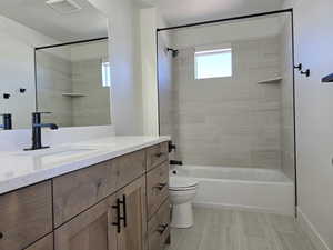 Full bathroom with tile patterned floors, vanity, toilet, and tiled shower / bath combo