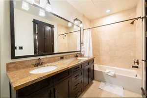 Bathroom featuring tile patterned flooring, vanity, and shower / tub combo with curtain