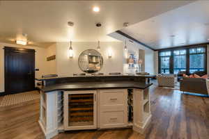 Kitchen with white cabinets, pendant lighting, wine cooler, and dark wood-type flooring