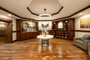 Interior space featuring dark hardwood / wood-style flooring, a raised ceiling, crown molding, and elevator