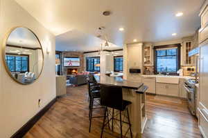 Kitchen featuring a kitchen breakfast bar, dark hardwood / wood-style flooring, stainless steel appliances, a center island, and a stone fireplace