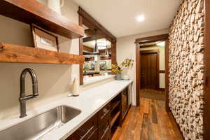 Kitchen with pendant lighting, dark hardwood / wood-style flooring, dark brown cabinetry, and sink