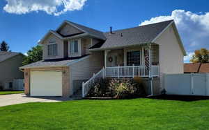 Tri-level home with a front yard, a porch, and a garage