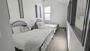 Carpeted bedroom with baseboard heating, ceiling fan, and lofted ceiling