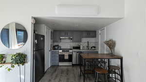 Kitchen with gray cabinetry, dark wood-type flooring, sink, tasteful backsplash, and stainless steel appliances