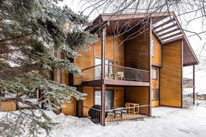 Snow covered back of property with a balcony