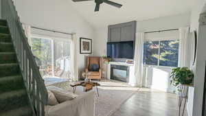 Living room with ceiling fan, high vaulted ceiling, and light hardwood / wood-style floors