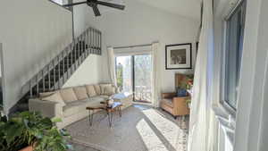 Living room with ceiling fan, high vaulted ceiling, and wood-type flooring