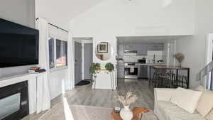 Living room with light wood-type flooring and high vaulted ceiling