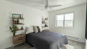 Bedroom featuring ceiling fan, dark hardwood / wood-style flooring, and a baseboard radiator