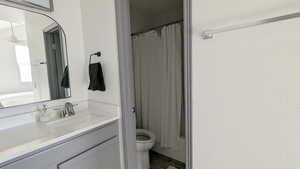 Full bathroom with ceiling fan, vanity, shower / tub combo, and toilet