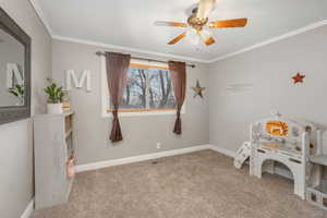 Recreation room with carpet, ceiling fan, and ornamental molding