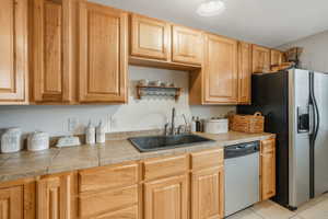 Kitchen with light tile patterned flooring, appliances with stainless steel finishes, and sink