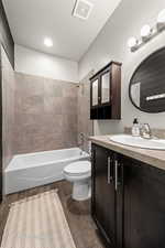 Full bathroom featuring hardwood / wood-style floors, vanity, tiled shower / bath combo, and a textured ceiling