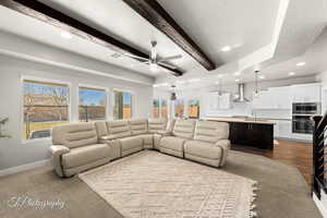 Living room with a textured ceiling, ceiling fan, sink, beamed ceiling, and light hardwood / wood-style floors