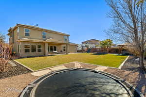 Rear view of house featuring a trampoline, a playground, and a lawn