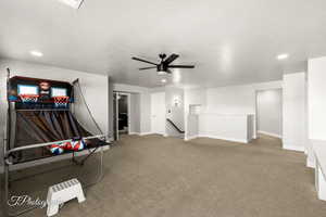 Rec room with carpet, ceiling fan, and a textured ceiling