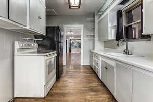 Kitchen featuring sink, white cabinetry, dark wood-type flooring, and electric stove