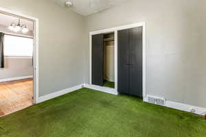 Unfurnished bedroom with a chandelier, a closet, dark carpet, and a textured ceiling