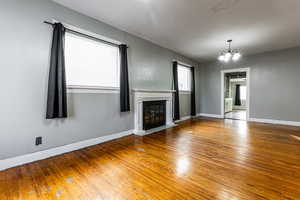 Unfurnished living room featuring hardwood / wood-style flooring, plenty of natural light, and an inviting chandelier