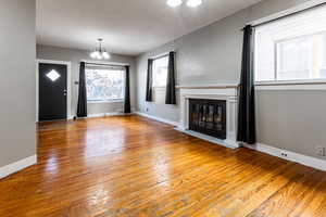 Unfurnished living room with hardwood / wood-style flooring and a notable chandelier