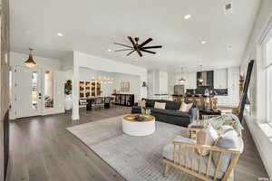 Living room with a wealth of natural light, dark hardwood / wood-style flooring, and ceiling fan with notable chandelier