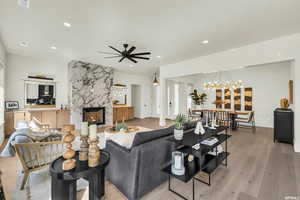 Living room featuring ceiling fan with notable chandelier, light hardwood / wood-style floors, and a high end fireplace