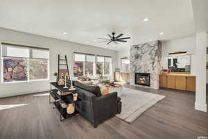 Living room with hardwood / wood-style floors, ceiling fan, and a premium fireplace