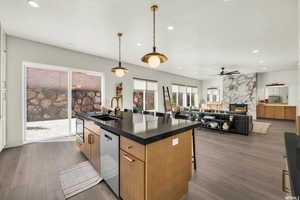 Kitchen featuring stainless steel appliances, ceiling fan, a kitchen island with sink, sink, and a fireplace