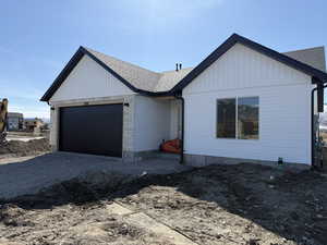 View of front of house with driveway, an attached garage, and a shingled roof