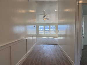 Hallway featuring a decorative wall, wood finished floors, a wainscoted wall, and a textured ceiling