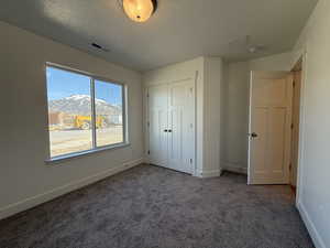 Unfurnished bedroom featuring a mountain view, baseboards, visible vents, and carpet floors