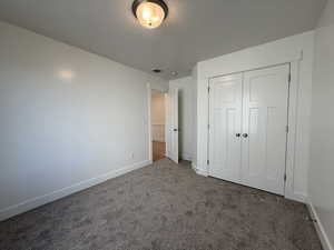 Unfurnished bedroom with visible vents, baseboards, carpet, a closet, and a textured ceiling